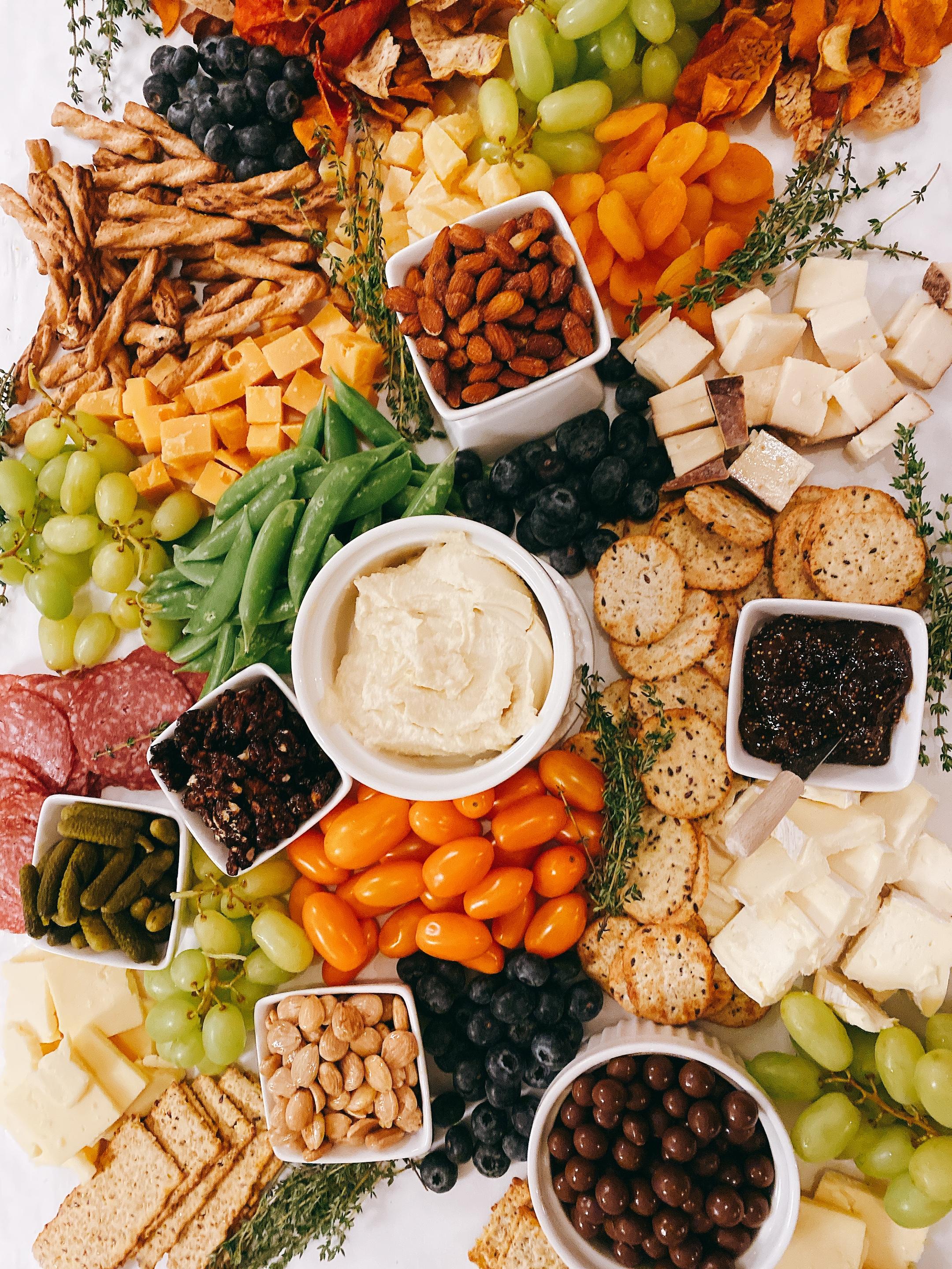 Lush charcuterie board styled with cheeses, cured meats, fresh herbs, and seasonal fruit